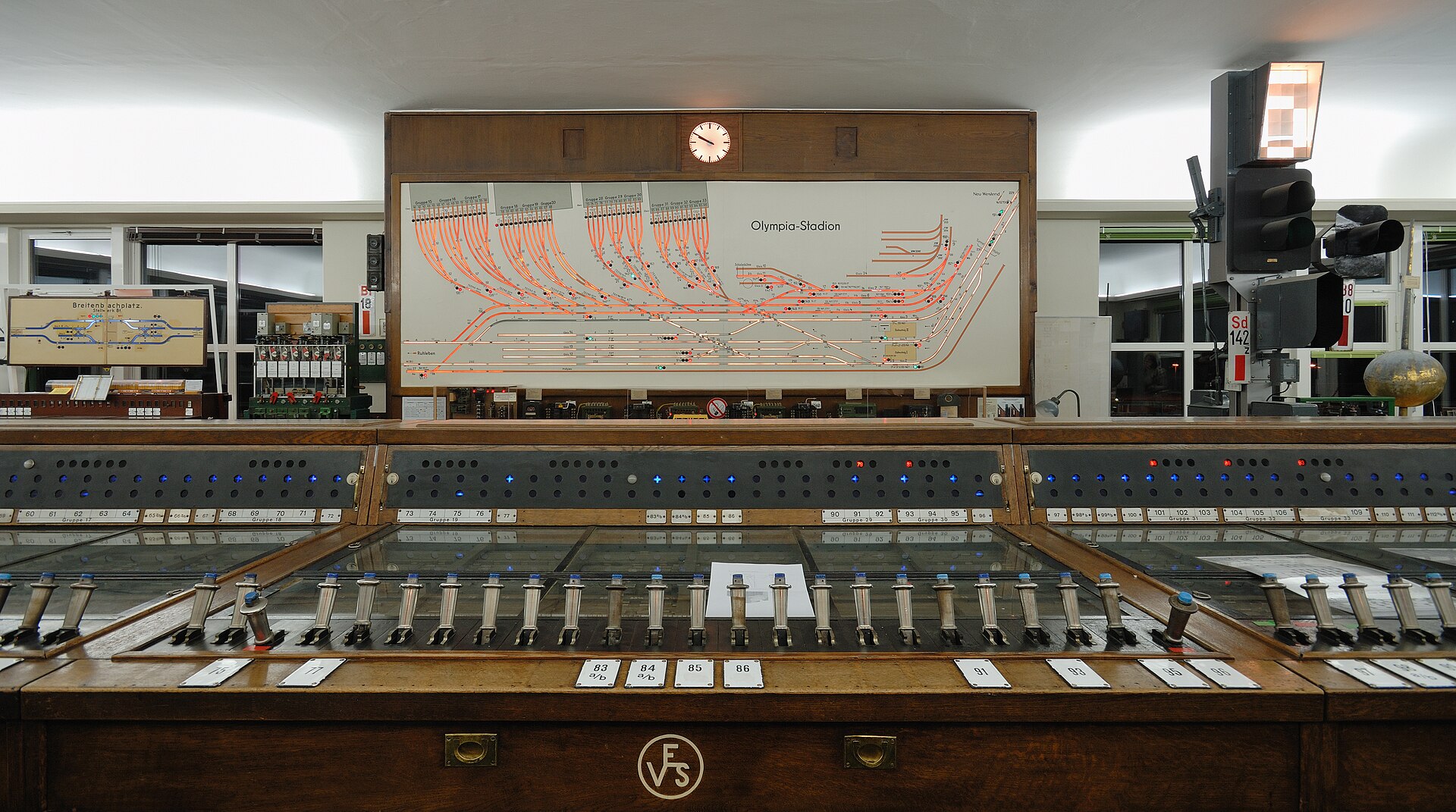 A railway interlocking panel: a lit track diagram above a long row of numbered levers, showing every valid route through the junction
